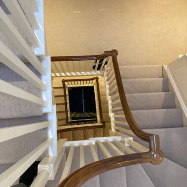 Refurbished staircase by painter and decorator in hampshire featuring a glossy wooden banister and white spindles.