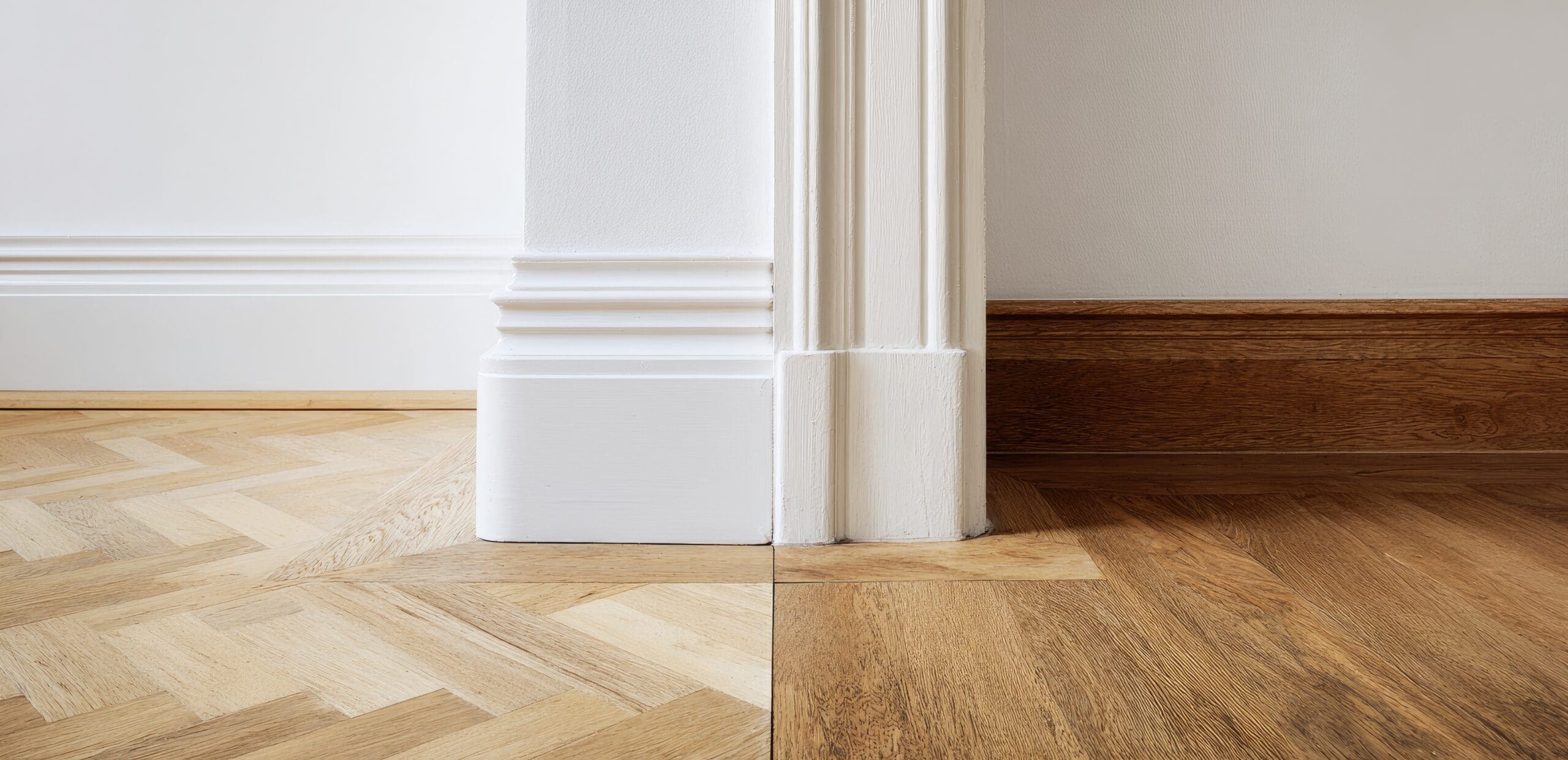 Interior corner with white skirting boards and herribone floors